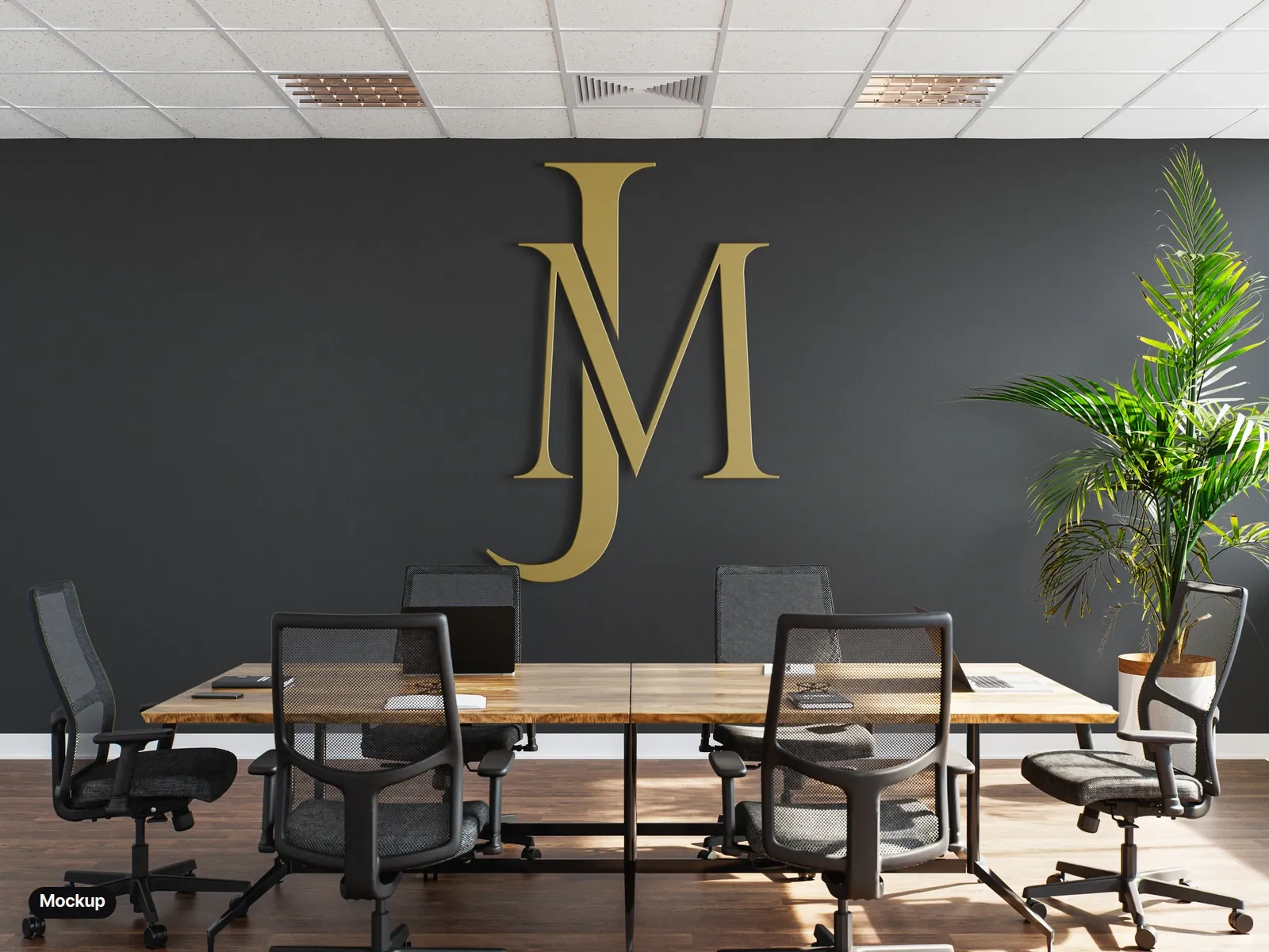 Mockup: the monogram as gold dimensional letters on a charcoal meeting-room wall, above a wooden table and black office chairs.